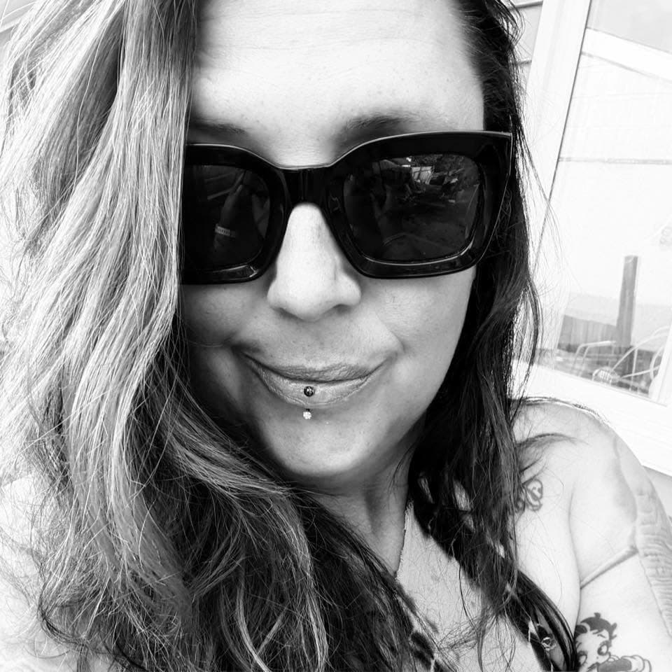 Black and white selfie of a woman wearing large sunglasses and a vertical labret piercing.